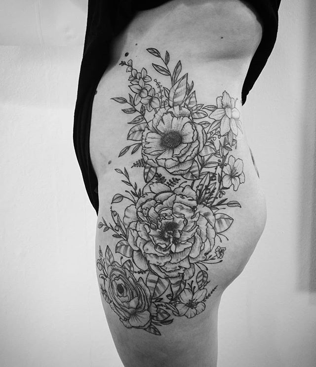 Foto eines Tattoos vieler Blumen auf der Seite einer Frau